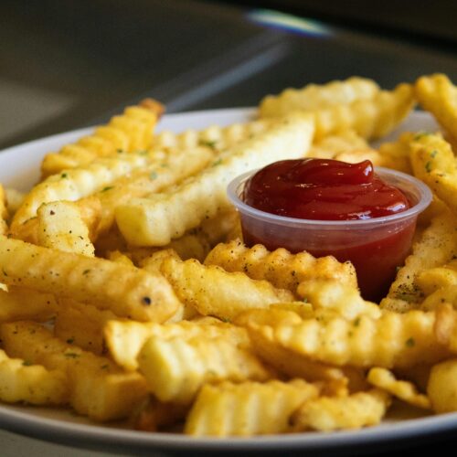 Golden crispy air fryer french fries in a white bowl with sea salt seasoning